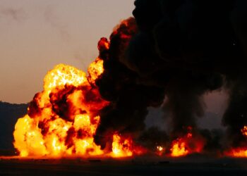 Une violente explosion, accompagnée de flammes éclatantes et d'une épaisse fumée noire, emplit le ciel au crépuscule.