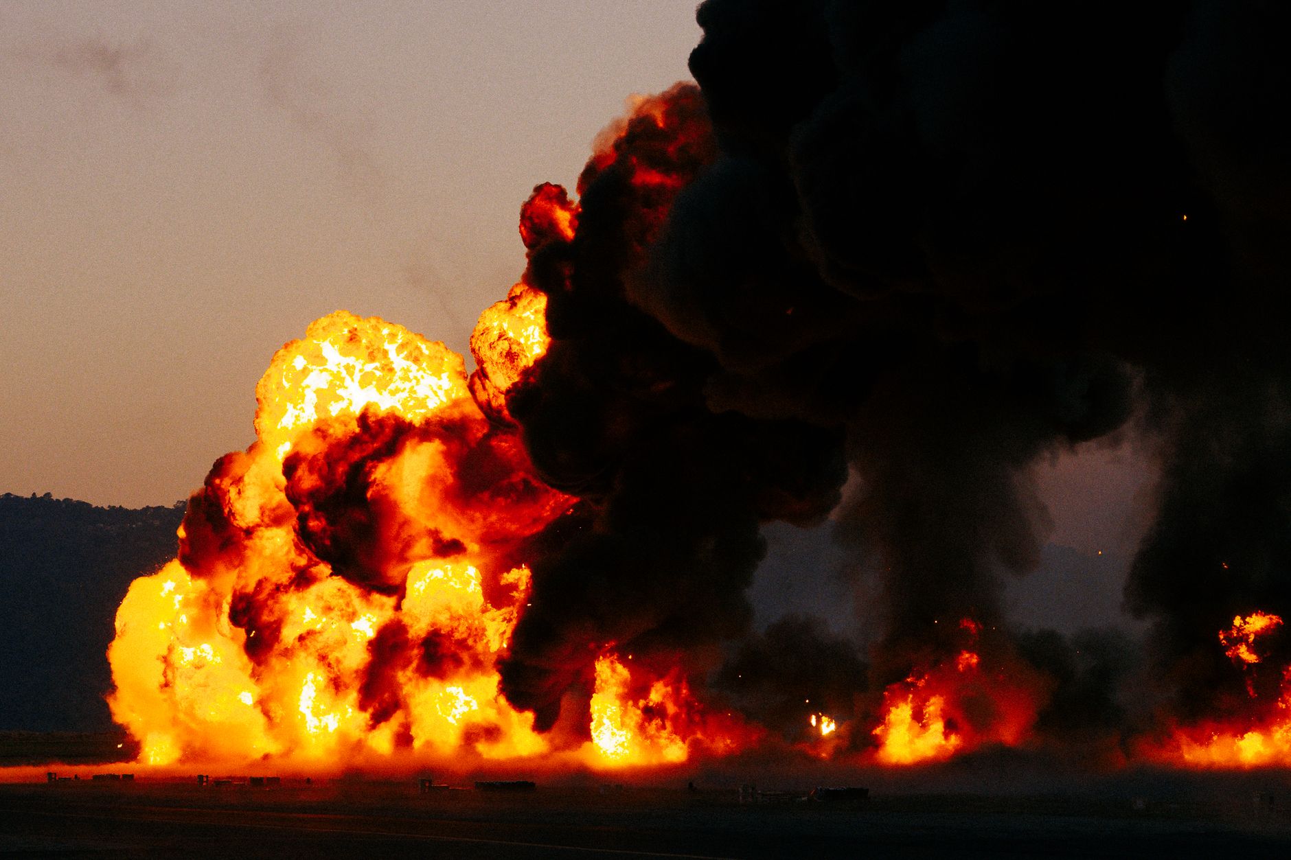 Une violente explosion, accompagnée de flammes éclatantes et d'une épaisse fumée noire, emplit le ciel au crépuscule.
