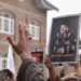 Des manifestants lèvent les mains en brandissant une affiche de Khamenei, exprimant leur désaccord en plein air.