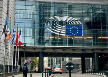 Vue extérieure du Parlement européen à Bruxelles, avec les drapeaux de l'UE déployés.