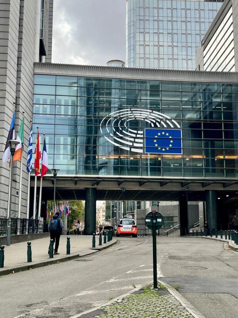 Vue extérieure du Parlement européen à Bruxelles, avec les drapeaux de l'UE déployés.