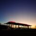 Une station-service sous un ciel d'aube dramatique capturant l'ambiance calme du petit matin.