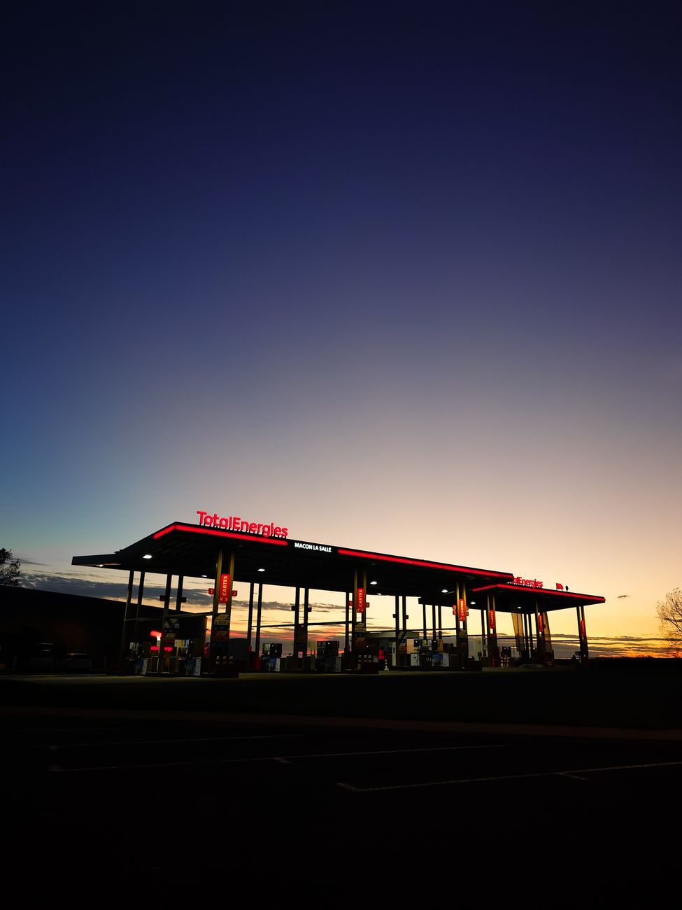 Une station-service sous un ciel d'aube dramatique capturant l'ambiance calme du petit matin.