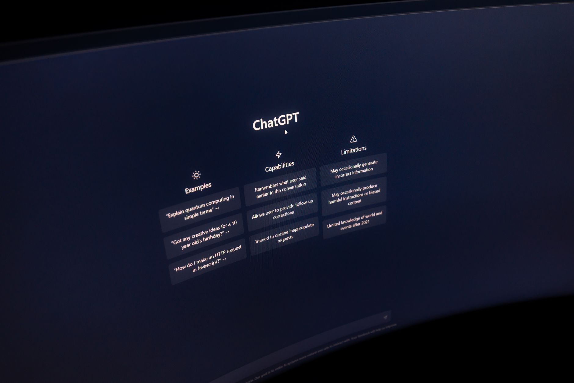 Gros plan sur un écran d'ordinateur affichant l'interface de ChatGPT dans un environnement sombre.