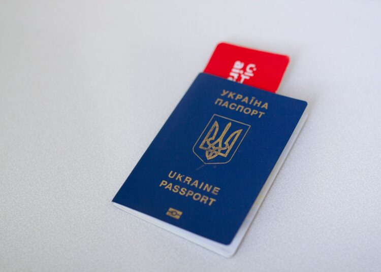 Passeport ukrainien bleu avec un billet d'avion sur une surface blanche. Concept de voyage.
