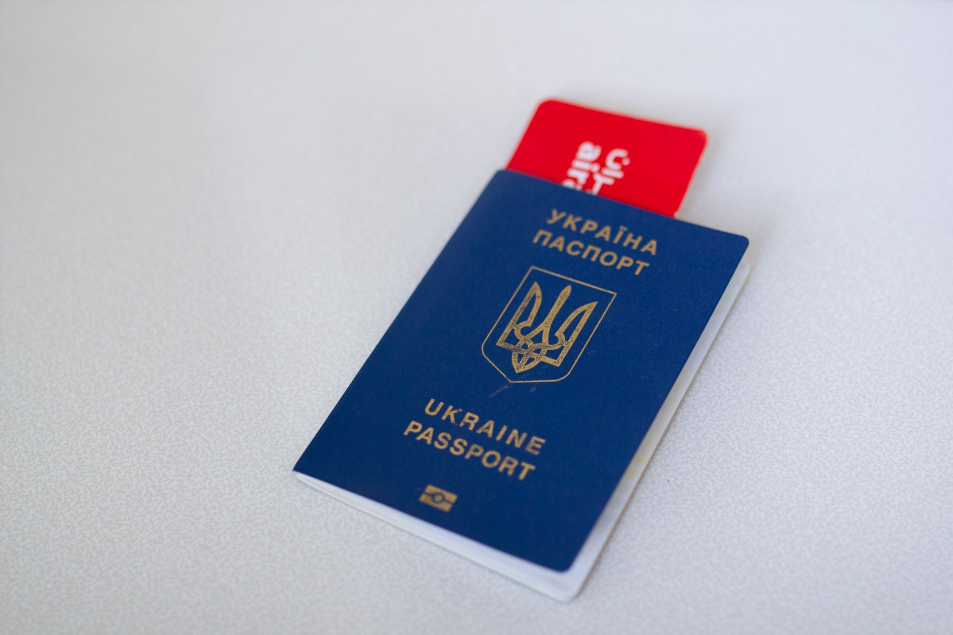 Passeport ukrainien bleu avec un billet d'avion sur une surface blanche. Concept de voyage.