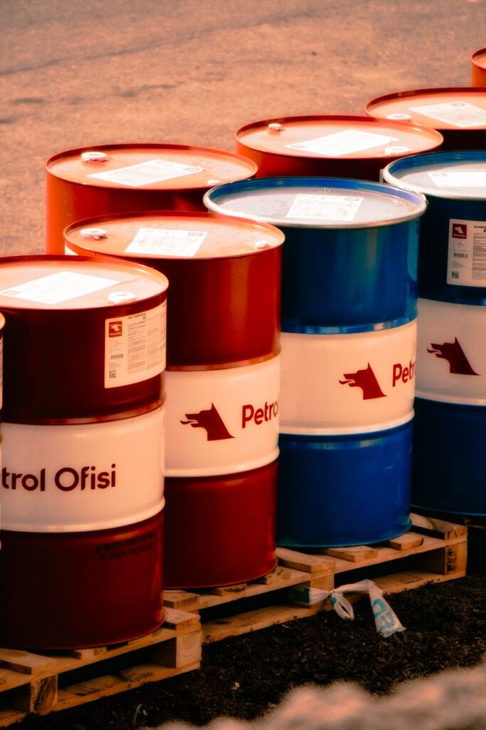 Une collection de barils de pétrole rouges et bleus étiquetés 'Ofisi de Pétrole' dans un cadre industriel en plein air en Turquie.