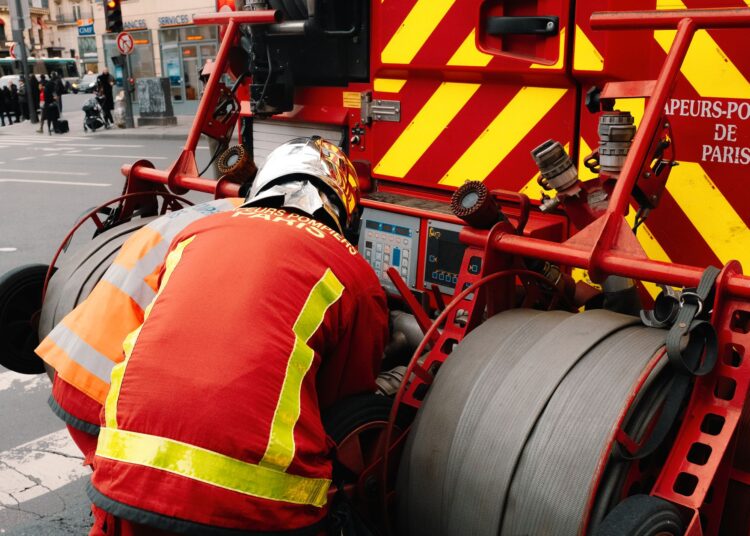 Pompiers utilisant l'équipement sur un camion de pompier à Paris, garantissant la sécurité publique.