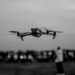 Une image en noir et blanc d'un drone survolant une foule à l'extérieur, mettant en valeur la technologie en vol.