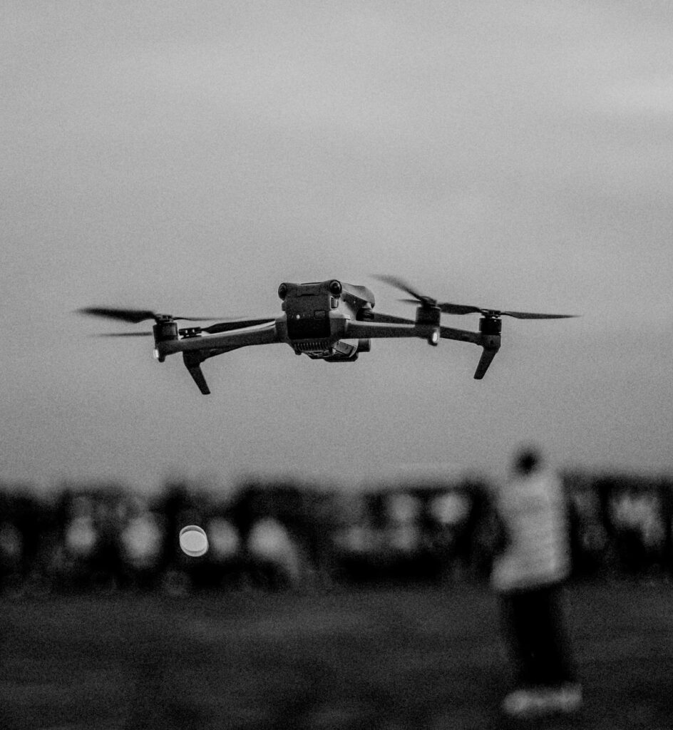 Une image en noir et blanc d'un drone survolant une foule à l'extérieur, mettant en valeur la technologie en vol.