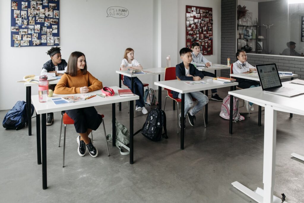 Groupe divers d'étudiants apprenant attentivement dans une salle de classe lumineuse.