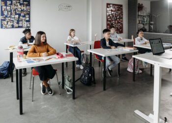 Groupe divers d'étudiants apprenant attentivement dans une salle de classe lumineuse.