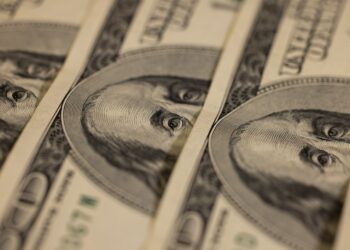 Prise de vue macro détaillée de plusieurs billets de dollar US mettant en valeur un design monétaire complexe.