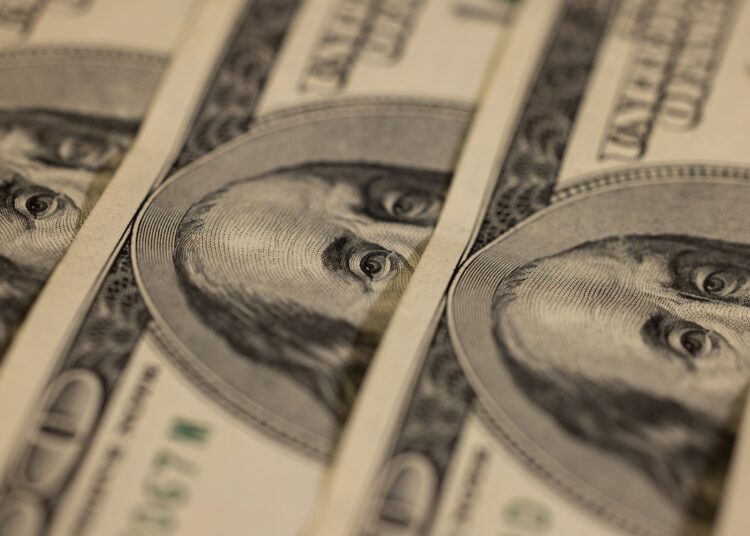 Prise de vue macro détaillée de plusieurs billets de dollar US mettant en valeur un design monétaire complexe.