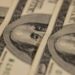 Prise de vue macro détaillée de plusieurs billets de dollar US mettant en valeur un design monétaire complexe.