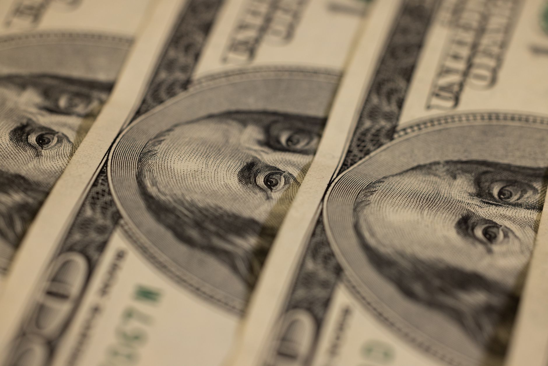 Prise de vue macro détaillée de plusieurs billets de dollar US mettant en valeur un design monétaire complexe.