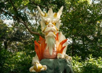 Gros plan sur une statue de dragon au milieu d'une végétation luxuriante à Fujisawa, au Japon, illustrant une beauté mythique.