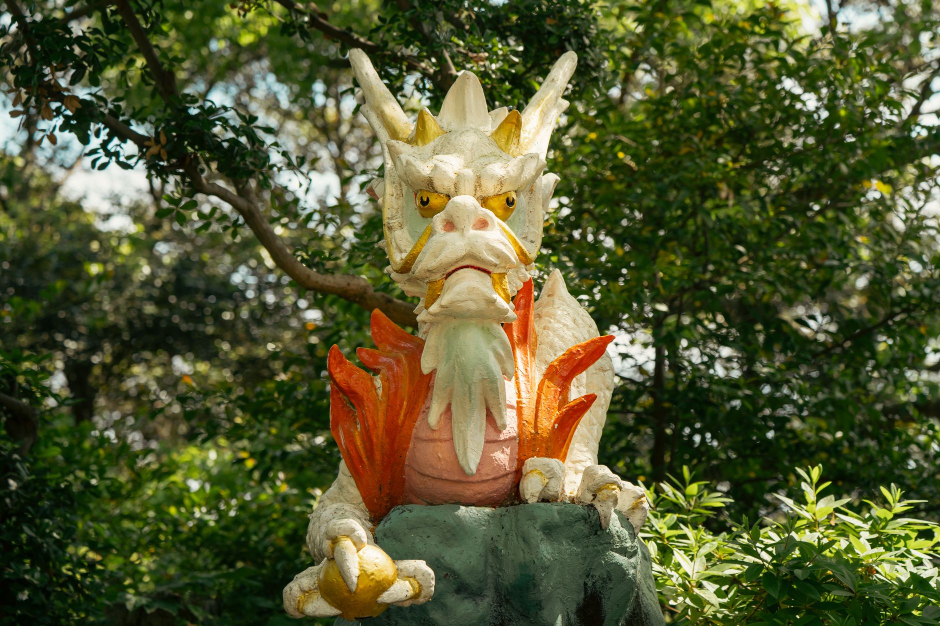 Gros plan sur une statue de dragon au milieu d'une végétation luxuriante à Fujisawa, au Japon, illustrant une beauté mythique.