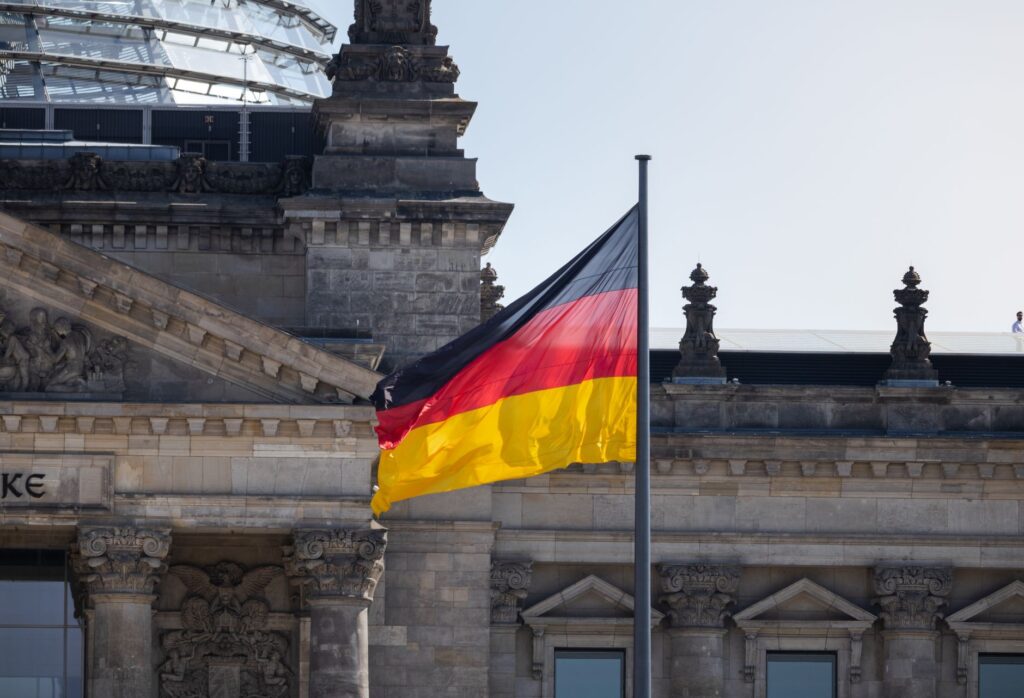 Le drapeau allemand flotte devant le célèbre bâtiment du Reichstag à Berlin, symbolisant la fierté nationale.