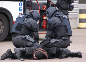 Des policiers allemands en tenue complète interpellent un suspect dans une zone urbaine à Hambourg.