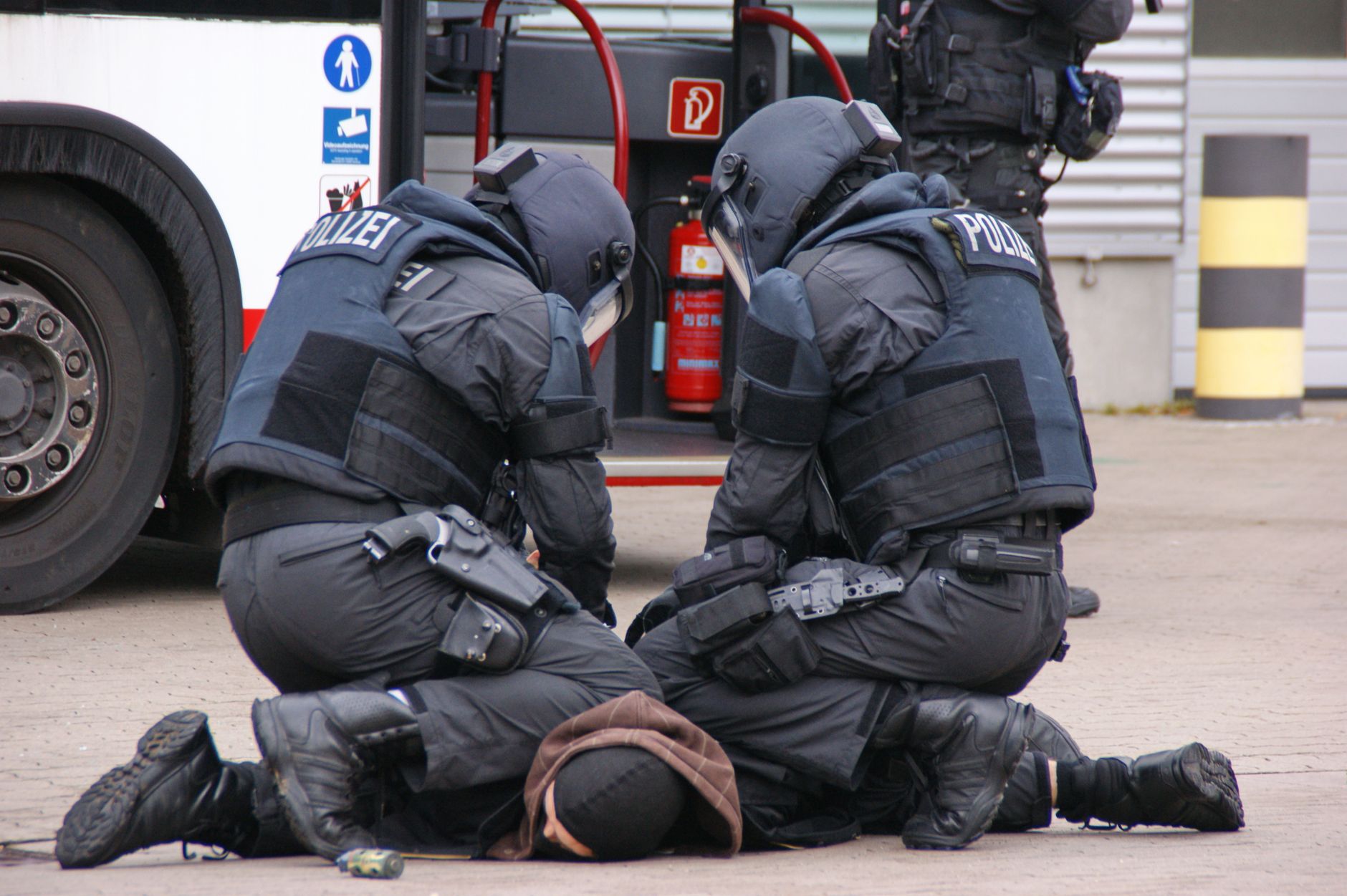 Des policiers allemands en tenue complète interpellent un suspect dans une zone urbaine à Hambourg.