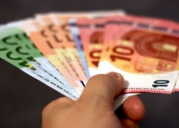 Gros plan d'une main tenant un éventail de billets en euros, symbolisant la richesse et l'échange de devises.