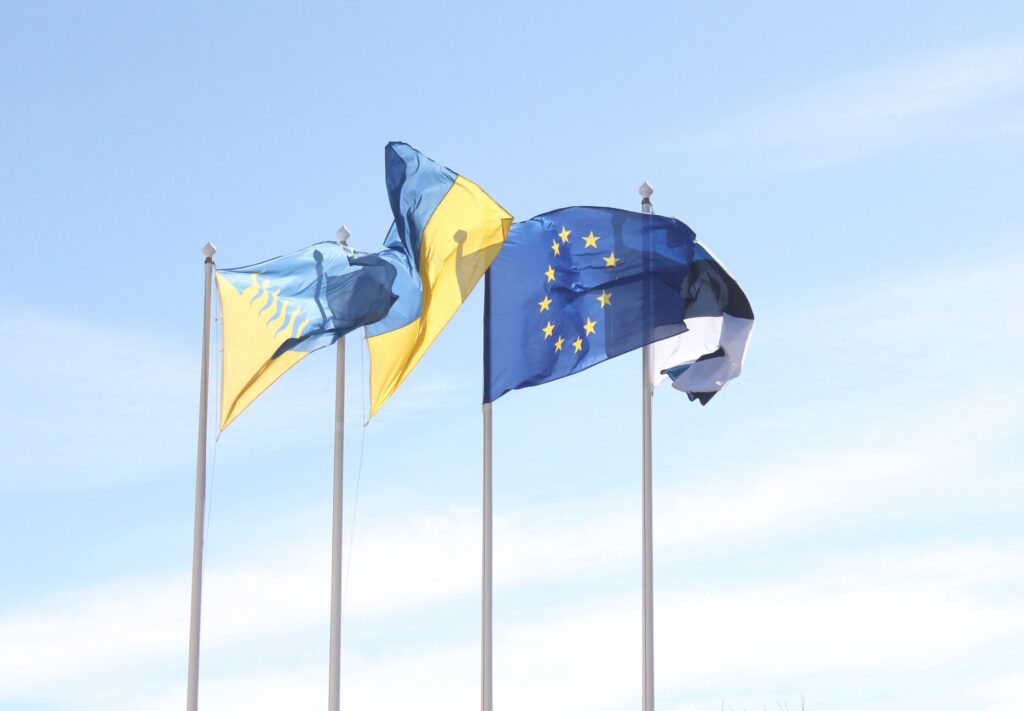 Les drapeaux de l'Union européenne et de l'Estonie flottent sous un ciel bleu dégagé, symbolisant l'unité et l'harmonie.
