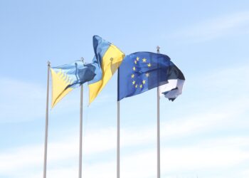 Les drapeaux de l'Union européenne et de l'Estonie flottent sous un ciel bleu dégagé, symbolisant l'unité et l'harmonie.