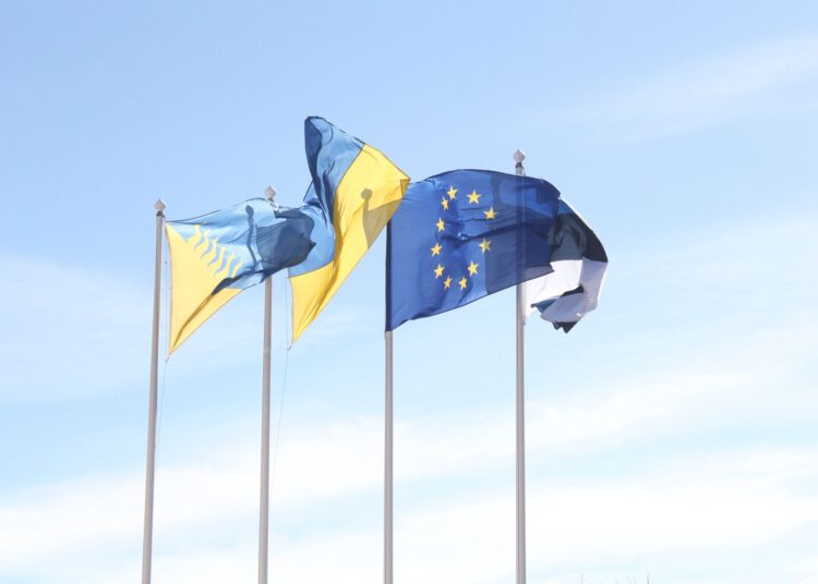 Les drapeaux de l'Union européenne et de l'Estonie flottent sous un ciel bleu dégagé, symbolisant l'unité et l'harmonie.