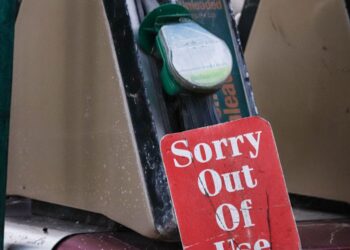 Image en gros plan d'une pompe à essence marquée d'un panneau hors service, mettant en avant la pénurie de carburant.